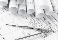 rolls of architecture blueprints and house plans on the table and drawing compass
